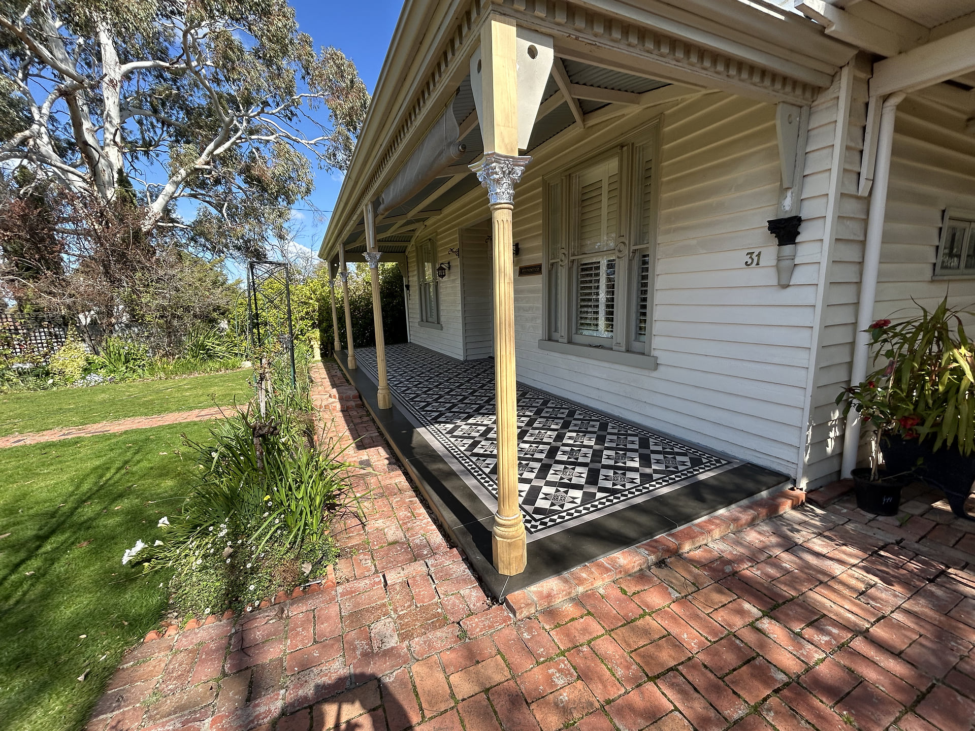 Country weatherboard house with a diagonal Paddington tiled verandah, lawn and gum tree, St Arnaud