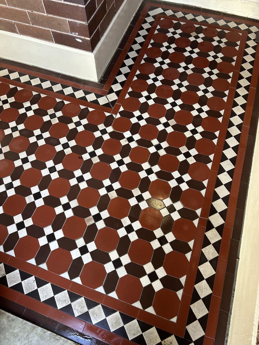 Restored corner of a brick red and black Nottingham verandah with a crisp Norwood border, Ashfield