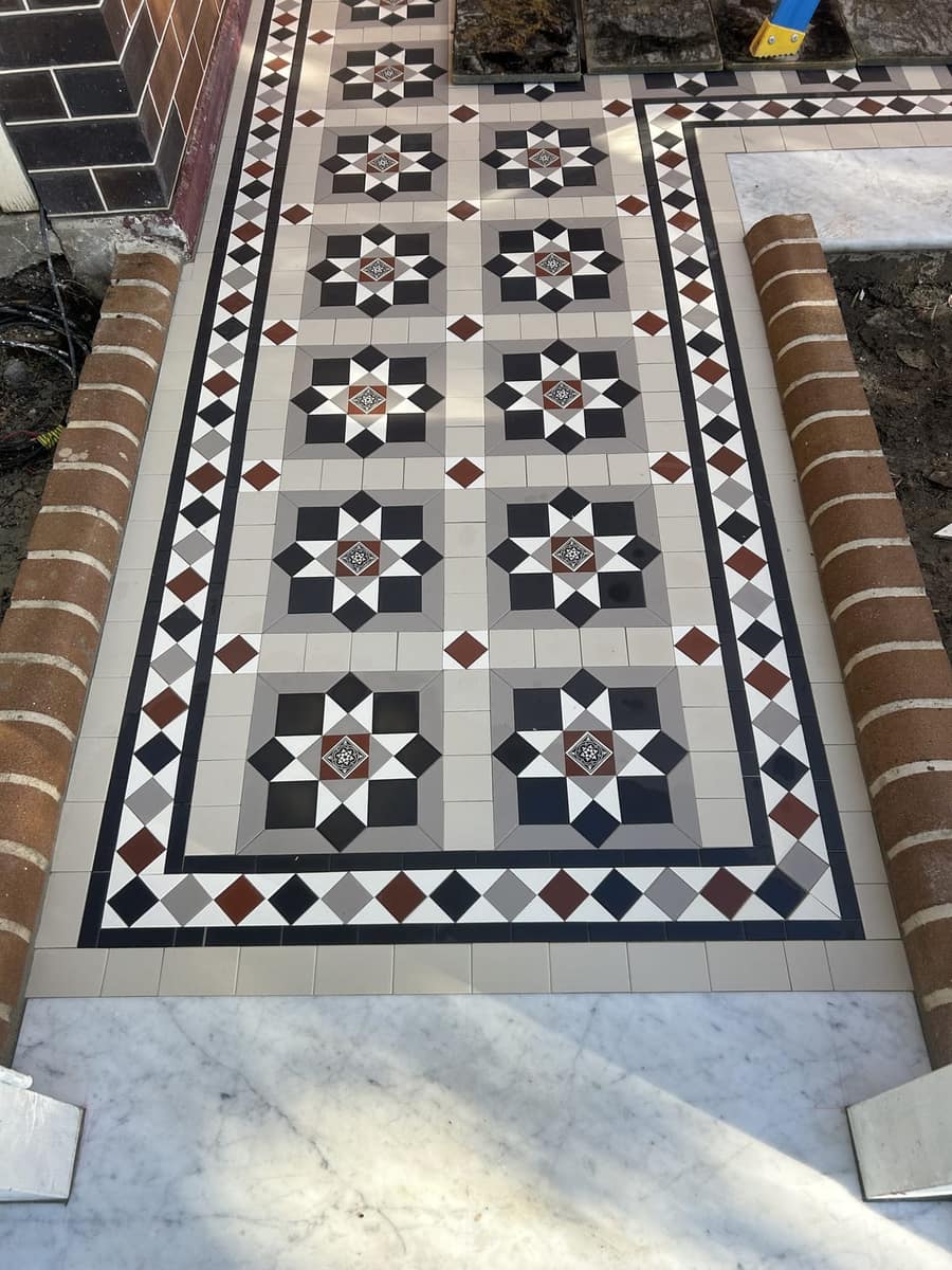Top-down of a cream Bristle path with black, grey and brick red and a Norwood border in sun, Leichhardt